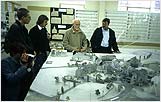 The supervising Art Director explains to the professor and students the steps for planning. One of many models, it depicts a village destroyed in the war.